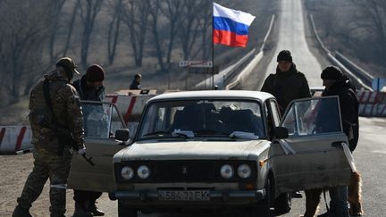Des militaires inspectent une voiture au check-point du village de Kremenevka, dans l'est de l'Ukraine, le 23 mars 2022. (MAKSIM BLINOV / SPUTNIK / AFP)