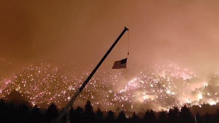 Un drapeau américain flotte devant les flammes de Lake Christine, le 4 juillet 2018, à Basalt dans le Colorado (Etats-Unis). (RONALD KIMBEL / CROWDSPARK)