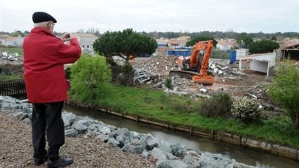 Un homme prend en photo un bulldozer qui détruit des habitations à La Faute-sur-Mer, un an après la tempête Xynthia (AFP - FRANK PERRY)