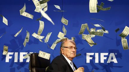 Sepp Blatter sous une pluie de billets de banque, jetés par un comédien britannique lors d'une conférence de presse organisée à Zurich (Suisse), le 20 juillet 2015.&nbsp;Alors président de la Fifa, le Suisse était grandement affaibli par l'affaire de corruption qui visait l'institution. (ARND WIEGMANN / REUTERS)