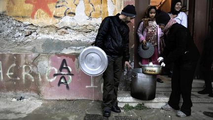 Une membre d'une association sert de la soupe &agrave; une famille pauvre &agrave; Ath&egrave;nes (Gr&egrave;ce), le 6 f&eacute;vrier 2012. (LOUISA GOULIAMAKI / AFP)