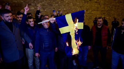 Des manifestants trucs brûlent le drapeau suédois devant le Consulat général de Suède, à Istanbul, le 21 janvier 2023. (YASIN AKGUL / AFP)