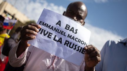 Un homme brandit une pancarte "à bas Emmanuel Macron, vive la Russie" lors d'une manifestation de masse à Bamako (Mali), le 14 janvier 2022. (FLORENT VERGNES / AFP)