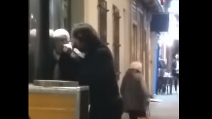 Capture d'écran de la vidéo révélée par Mediapart où l'on voit un jeune mineur maintenu par un policier en civil, la tête couverte d'un tissu. (MEDIAPART / YOUTUBE)