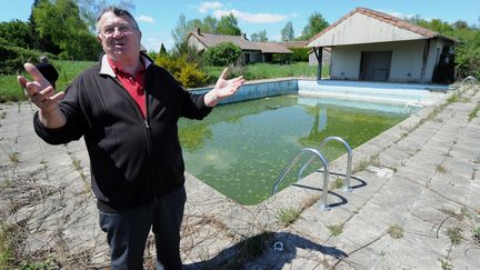 Le maire de Saint-Nicolas-Courbefy, Bernard Guilhem, se tient le 16 mai 2012 devant la piscine du hameau de Courbefy, mis en vente aux ench&egrave;res le 21 mai. (PASCAL LACHENAUD / AFP)