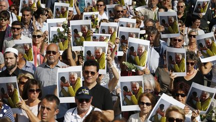 Quelque 2 000 portraits d'Herv&eacute; Gourdel, ainsi qu'un millier de roses blanches, ont &eacute;t&eacute; distribu&eacute;s par la mairie de Nice, organisatrice de cette marche en accord avec la famille, le 27 septembre 2014.&nbsp; (VALERY HACHE / AFP)