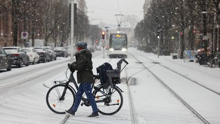 Une femme pousse son vélo sur une route couverte de neige à Strasbourg (Bas-Rhin), le 14 décembre 2022. (JEAN-FRANCOIS BADIAS / AP / SIPA)