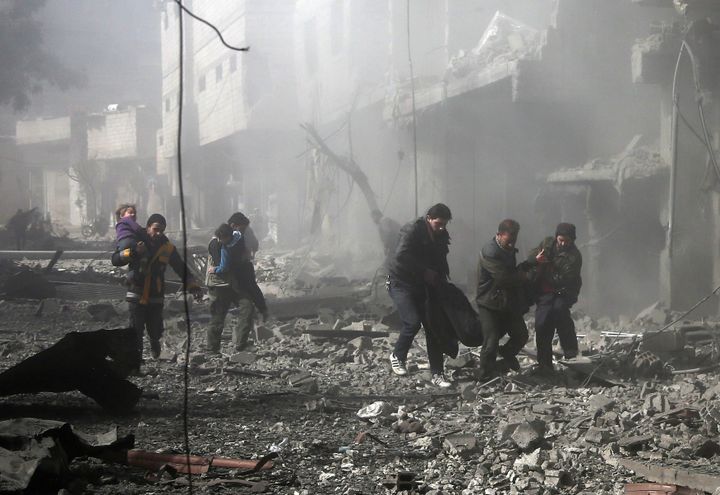 Des hommes transportent une victime après le bombardement d'un bâtiment dans la Ghouta orientale, près de Damas (Syrie), le 19 février 2018. (ABDULMONAM EASSA / AFP)