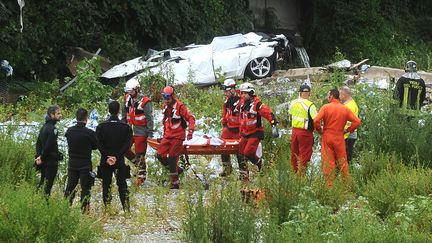 Des secouristes transportent un corps sur le lieu de l'effondrement du pont Morandi, à Gênes (Italie), le 14 août 2018. (REUTERS)