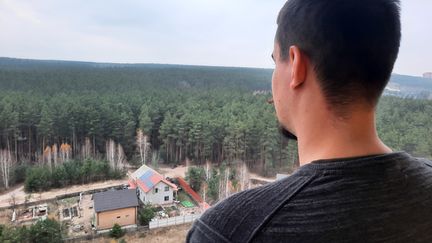 Sacha face à la forêt d'Irpin brûlée devant chez lui, en Ukraine. (CLAUDE GUIBAL / RADIOFRANCE)