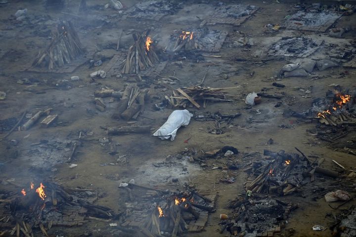 Un corps est étendu au sol près de bûchers funéraires de victimes du Covid-19 à New Delhi (Inde), le 26 avril 2021. (MONEY SHARMA / AFP)