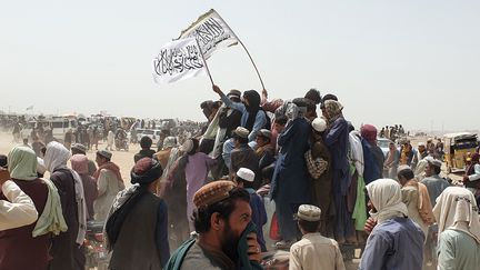 Des personnes brandissent le drapeau des talibans,&nbsp;près de la frontière pakistanaise, le 14 juillet 2021. (ASGHAR ACHAKZAI / AFP)