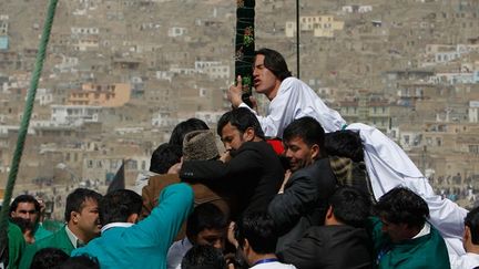 Des Afghans essayent d'embrasser un drapeau religieux.
  (REUTERS/Omar Sobhani)