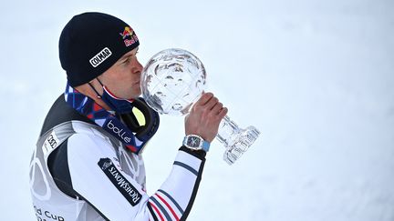 Alexis Pinturault embrasse le gros globe de Cristal, trophée pour le vainqueur du classement général de la Coupe du monde de ski alpin, le 20 mars 2021. (FABRICE COFFRINI / AFP)