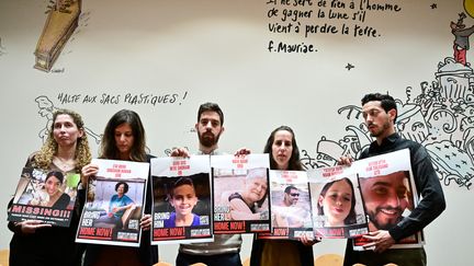 Des proches, dont le frère d'Elya Toledano à droite, montrent les photos d'otages du Hamas à l'Assemblée nationale, le 31 octobre 2023. (MIGUEL MEDINA / AFP)