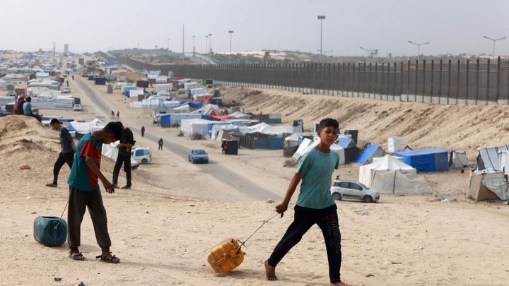 Des enfants traînent des bidons remplis d'eau jusqu'à leur tente aux abords de Rafah, le 26 avril 2024. (MOHAMMED ABED / AFP)