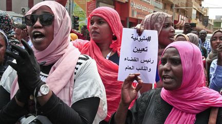 Lors d'une manifestation de masse le 12 septembre 2019 près du palais présidentiel à Khartoum, des femmes brandissent une pancarte sur laquelle on peut lire "un million de manifestants vont nommer le nouveau chef de l'appareil judiciaire et un nouveau procureur général". (EBRAHIM HAMID / AFP)