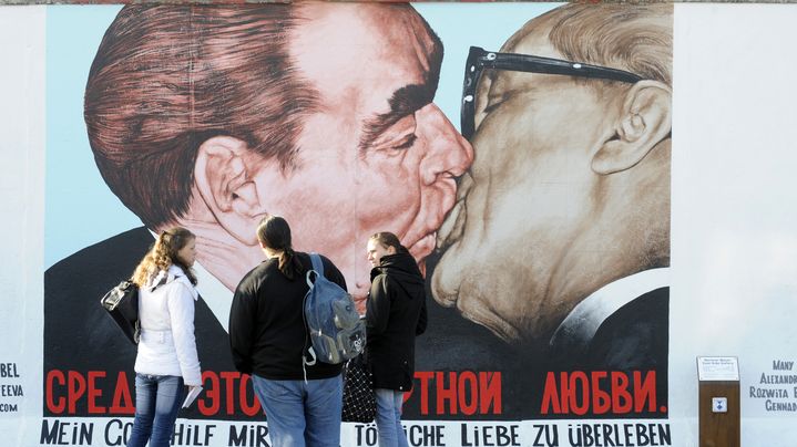 Des personnes se tiennent devant l'East Side Gallery et son c&eacute;l&egrave;bre "baiser fraternel" entre Honecker et Brejnev, peint par le Russe&nbsp;Dmitry Vrubel,&nbsp;le 20 octobre 2009 &agrave; Berlin (Allemagne). (JOHN MACDOUGALL / AFP)