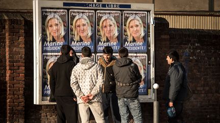 Des migrants devant des affiches de campagne de Marine Le Pen, tête de liste FN en Nord-Pas-de-Calais-Picardie, le 7 décembre&nbsp;2015 à Calais. (PHILIPPE HUGUEN / AFP)