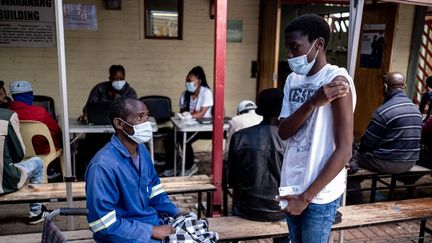 Un père et son fils&nbsp;vaccinés contre le Covid-19 à la clinique Witkoppen de Johannesburg, le 8 décembre 2021. (EMMANUEL CROSET / AFP)