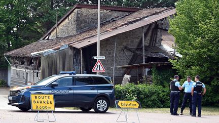 Des gendarmes bloquent&nbsp;la route menant à la maison&nbsp;où a eu lieu le drame à Douvres&nbsp;(Ain), le 20 juillet 2022. (JEAN-PHILIPPE KSIAZEK / AFP)