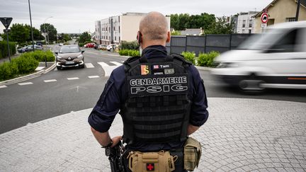 Un gendarme du Peloton de surveillance et d'intervention de la gendarmerie surveille les véhicules qui passent à un rond-point de Montreuil-Juigné, le 4 juillet 2023, dans le cadre de la traque d'un fugitif. (LOIC VENANCE / AFP)