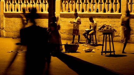 Les enfants doivent se rendre chaque soir sous les lampadaires publics afin d’étudier leurs leçons, comme ici Blaise et son frère Sylvain. Des vendeuses profitent également de cet éclairage pour présenter leur marchandise.  (Pascal Maitre/Cosmos)