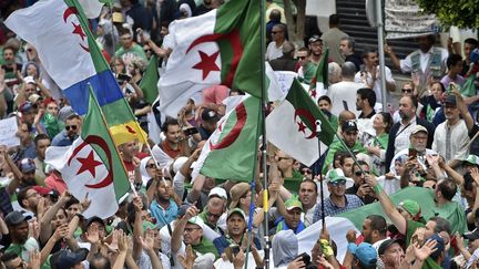 Les manifestants algériens agitent des drapeaux nationaux lors d'une manifestation antigouvernementale devant le Grande-Poste à Alger, le 24 mai 2019. (RYAD KRAMDI / AFP)