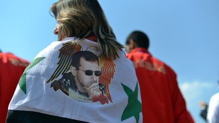 Une supportrice syrienne portant un drapeau de son pays &agrave; l'effigie de Bachar Al-Assad, dans le village olympique de Londres (Royaume-Uni), le 25 juillet 2012.&nbsp; (SAEED KHAN / AFP)