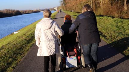 Un homme handicapé soutenu par des aidants familiaux, sa femme et sa fille, à Thionville le 22 novembre 2017. (JULIO PELAEZ / MAXPPP)