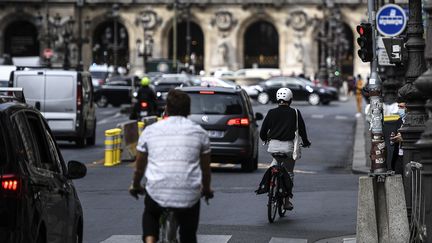 Une cycliste grille un feu rouge dans le trafic parisien, le 23 septembre 2020. (CHRISTOPHE ARCHAMBAULT / AFP)