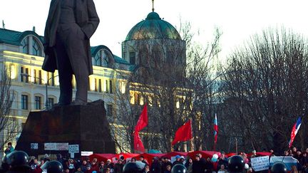 A Donetsk, dans l'est de l'Ukraine, des partisans de la Russie brandissent des drapeaux rouges et russes au pied d'une statue de Lénine, le 13 mars 2014. Dans cette ville, des affrontements entre partisans des deux camps ukrainiens ont fait un mort. (BAHADIR VANLI/AFP)