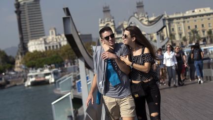 Un couple de touristes se promène sur la marina de Barcelone, le 13 octobre 2017. Photo d'illustration. (JORGE GUERRERO / AFP)