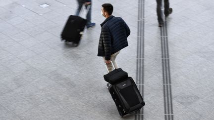 Un voyageur marche avec un bagage dans le hall de départ de la gare de Lyon à Paris, le 18 décembre 2020. (STEPHANE DE SAKUTIN / AFP)