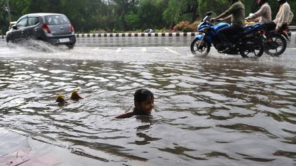 Un jeune Indien joue dans une rue inond&eacute;e de New Delhi (Inde), le 12 juillet 2012. (SAJJAD HUSSAIN / AFP)