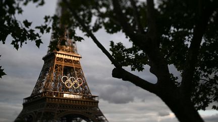 Les anneaux olympiques sur la tour Eiffel, à Paris, le 23 juillet 2024. (SEBASTIEN BOZON / AFP)