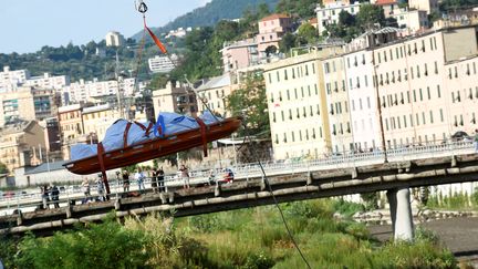 Les secours transportent un corps après l'effondrement du pont Morandi à Gênes, le 14 août 2018. (MASSIMO PINCA / REUTERS)