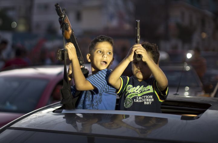 Deux enfants brandissent des armes pour c&eacute;l&eacute;brer le cessez-le-feu dans les rues de Gaza, mercredi 26 ao&ucirc;t.&nbsp; (MAHMUD HAMS / AFP)