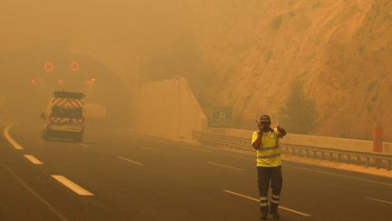 Un volontaire dirige les véhiculent alors que les flammes embrasent les forêts de Kineta, près d'Athènes, le 23 juillet 2018.&nbsp; (ALKIS KONSTANTINIDIS / REUTERS)