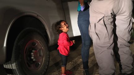 Une petite fille hondurienne de 2 ans, en pleurs alors que sa mère est fouillée par les patrouilles de sécurité aux frontières, à McAllen, au Texas, le 12 juin 2018.&nbsp; (JOHN MOORE / GETTY IMAGES / AFP)