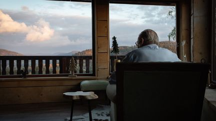 Assis dans son fauteuil, un monsieur regarde par la fenêtre, le 18 octobre 2020, au Tholy (Vosges). (LEO PIERRE / HANS LUCAS / AFP)