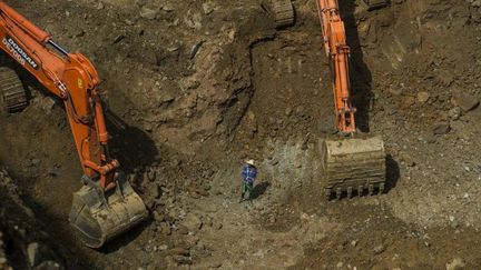 Un mineur entouré de pelleteuses dans une mine de jade dans la région de Hpakant, dans l'Etat de Kachin en Birmanie. (STR / AFP)