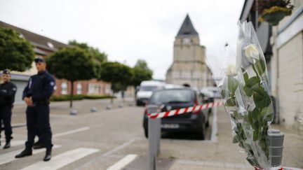 Des roses devant un cordon de police installé devant une église de Saint-Etienne-du-Rouvray (Seine-Maritime), le 27 juillet 2016. (CHARLY TRIBALLEAU / AFP)