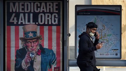 Un Américain passe devant une affiche "Medicare for All" à Washington, DC, le 3 juin 2020. (OLIVIER DOULIERY / AFP)