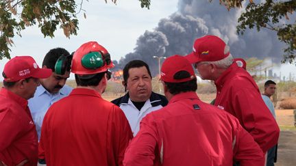 Hugo Chavez (au centre) avec les employ&eacute;s de la raffinerie d'Amuay (Venezuela), ravag&eacute;e par une explosion le 25 ao&ucirc;t 2012.&nbsp; (PRESIDENCIA / AFP)