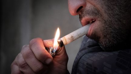 Un homme allume une pipe à crack. Image d'illustration. (JOEL SAGET / AFP)