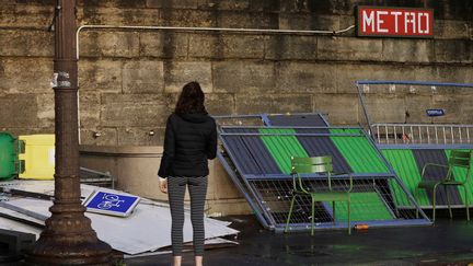 Une femme devant des dégâts matériels d'une station de métro, le 2 décembre 2018. (GEOFFROY VAN DER HASSELT / AFP)