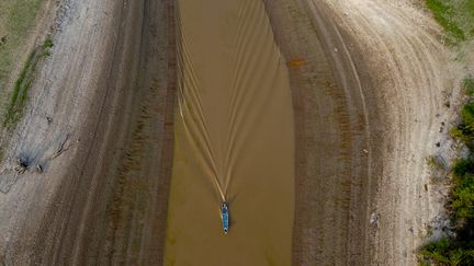 Un bateau navigue sur ce qu'il reste d'un canal vers le lac Puraquequara, à Manaus, au Brésil, le 6 octobre 2023. (MICHAEL DANTAS / AFP)