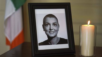 Une photo de Sinead O'Connor au Mansion House, à Dublin (Irlande), trône aux côtés d'un livre de condoléances ouvert suite à son décès, le 28 juillet 2023. (BRIAN LAWLESS/AP/SIPA / SIPA)