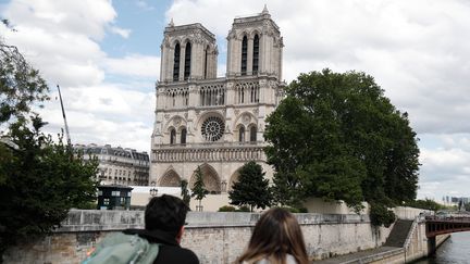 Deux touristes ont les yeux rivés sur Notre-Dame de Paris.&nbsp; (ZAKARIA ABDELKAFI / AFP)